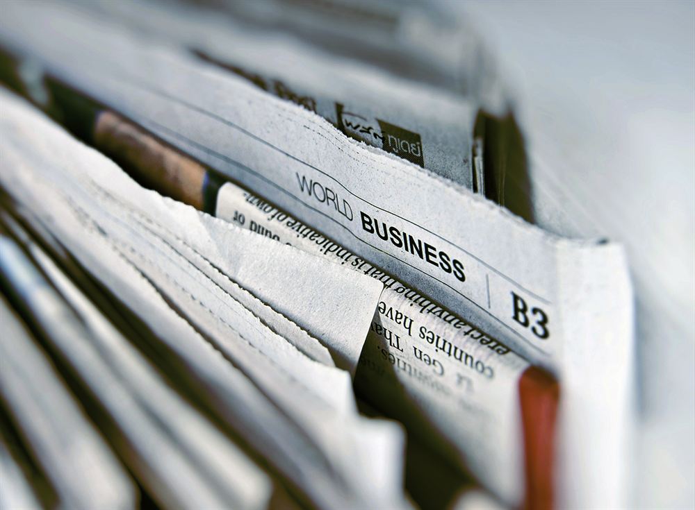 A close-up of a folded stack of newspapers, showing a World Business section.