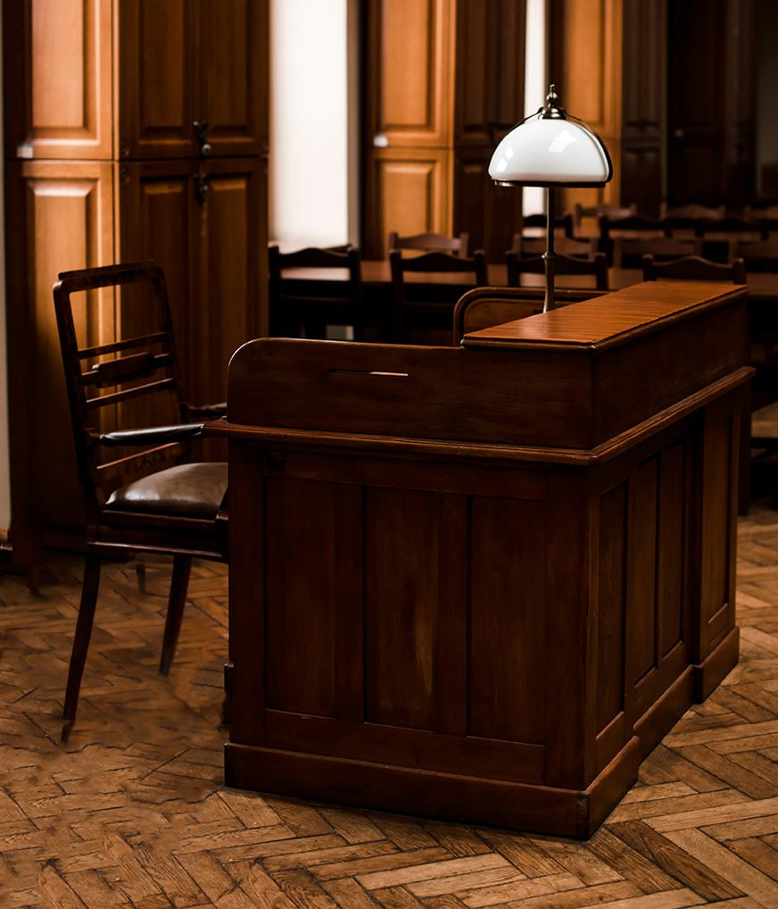 A wooden gavel resting on an open book, on top of a stack of leather-bound legal volumes.